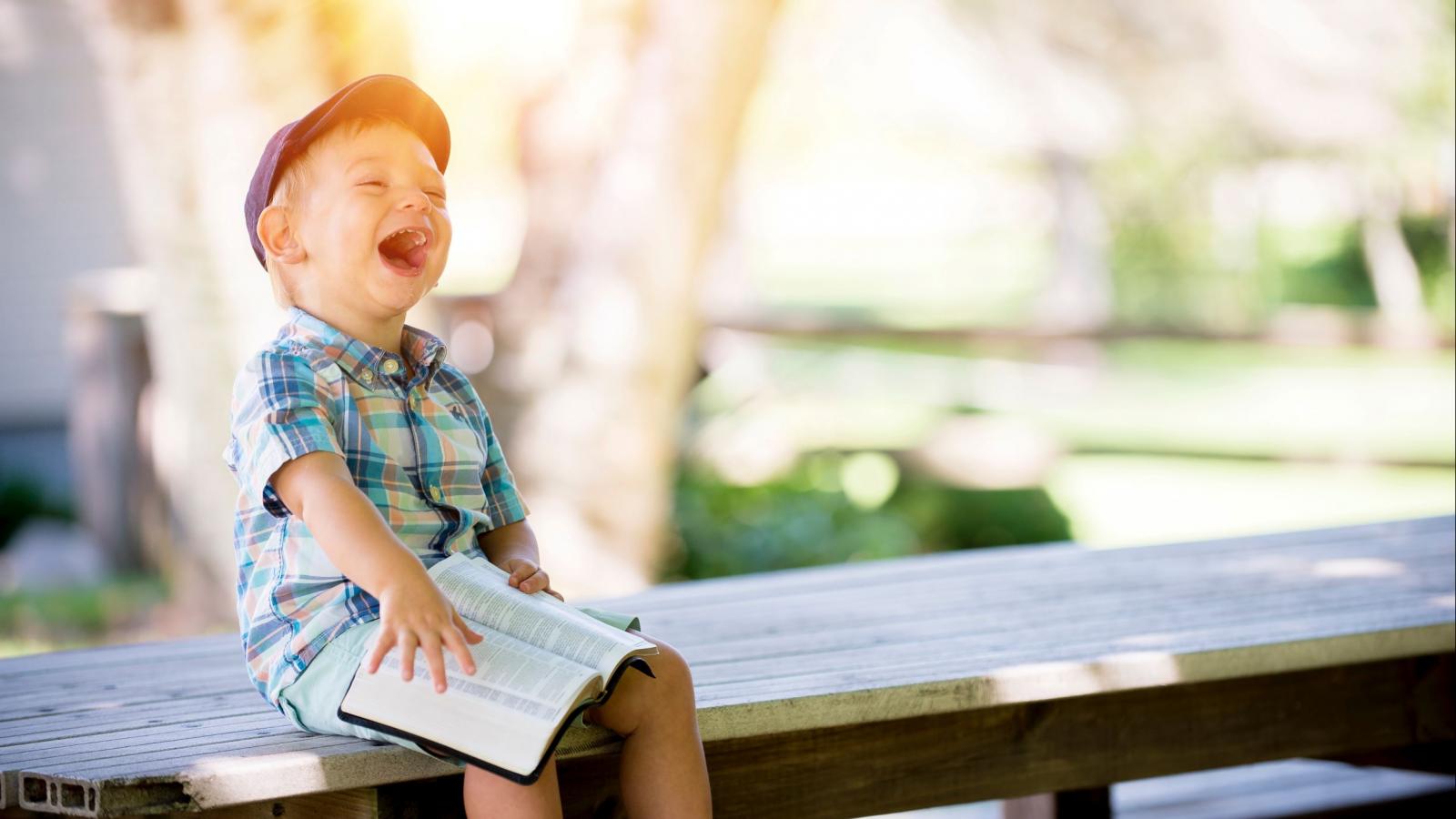 Young boy reading a book outside