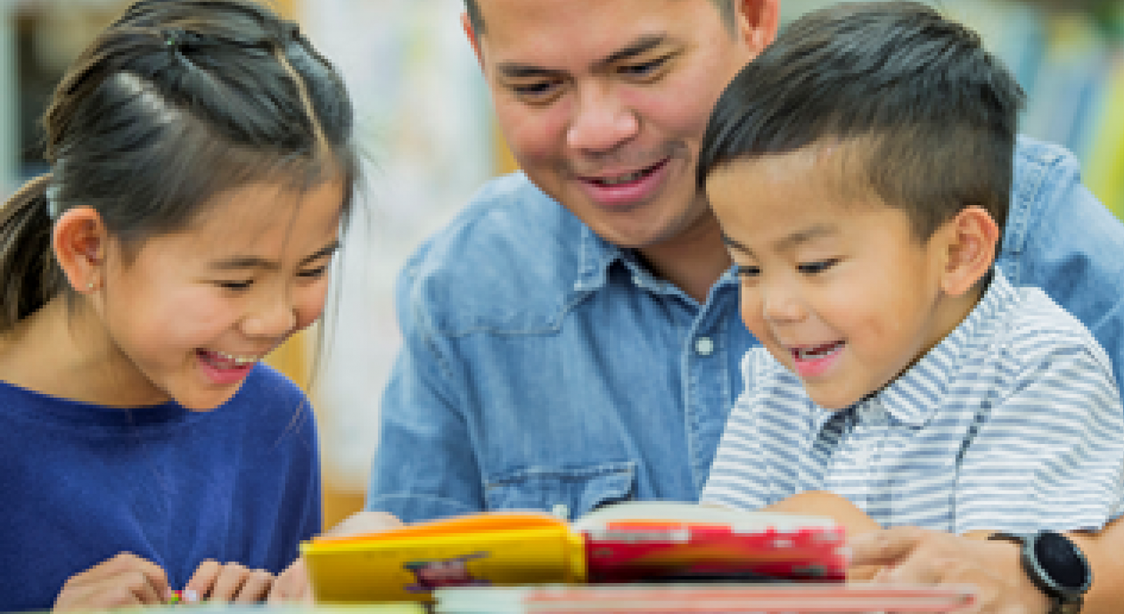 A man with a young girl and boy looking at a book