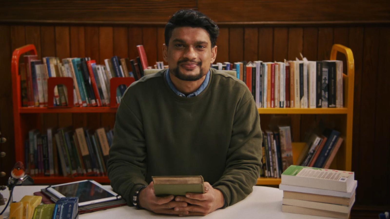 A librarian sitting at a desk with a welcoming smile